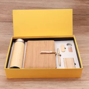 executive-bamboo-wooden-corporate-gift-set-yellow-box.jpg Luxury executive corporate gift set including a bamboo water bottle, wood-grain notebook, gold pen, USB drive, keychain, and card holder in an open yellow gift box.