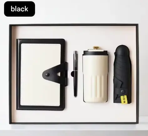 Executive corporate gift box containing a black and cream snap-closure notebook, a sleek metal pen, a cream insulated tumbler, and a black compact umbrella.