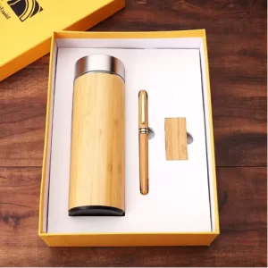 Luxury eco-friendly corporate gift set with a bamboo water bottle, matching pen, and wooden USB flash drive arranged inside a bright yellow presentation box.