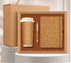 Eco-friendly corporate gift box containing a natural cork travel tumbler, a matching cork notebook, and a pen neatly presented in a kraft paper package.