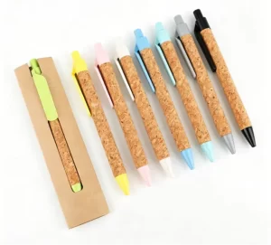 A row of eco-friendly retractable natural cork ballpoint pens with colorful pastel clips and tips alongside a kraft paper sleeve.