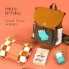 The Celebration Pack: Backpack, Blanket & Travel Mug Birthday Bundle A "Happy Birthday" corporate gift box set displayed against an orange background. The set includes a two-tone mustard brown and grey casual travel backpack, a rolled brown and white checkered blanket wrapped in a "Happy Birthday" sleeve, a birthday cake building-block toy box, and a teal ribbed travel coffee mug.