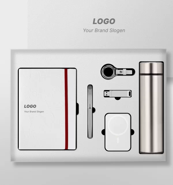 Premium customized executive corporate gift set laid out in a white presentation box, featuring a white notebook with a red elastic band, a sleek metal pen, a USB flash drive, a multi-connector charging cable, a wireless power bank, and a stainless steel thermal water bottle.