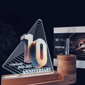 Illuminated company anniversary acrylic award with a wooden LED base, rotating perpetual calendar, pen holder, and branded gift box.