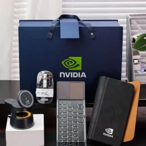 A corporate gift set featuring a blue gift box, a transparent electronic mouse, a multi-device wireless keyboard, a multi-function wireless charging station, and a portfolio notebook arranged on a desk. Executive Tech & Office Gift Set