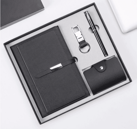 Executive 4-Piece Leatherette Gift Set – Notebook, Pen, Keychain, and Card Holder Black leatherette 4-piece corporate gift set featuring a notebook with a metallic buckle, a black pen, a key chain, and a snap card holder in a gift box.