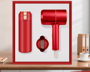 luxury-red-hairdryer-vacuum-flask-corporate-gift-set Luxury red corporate gift set featuring a sleek ionic hair dryer with gold trim, detachable nozzle, and matching stainless steel vacuum flask in a red presentation box.